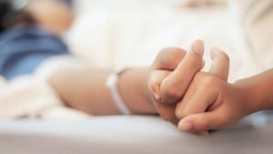 Patient holds hands of hospital volunteer